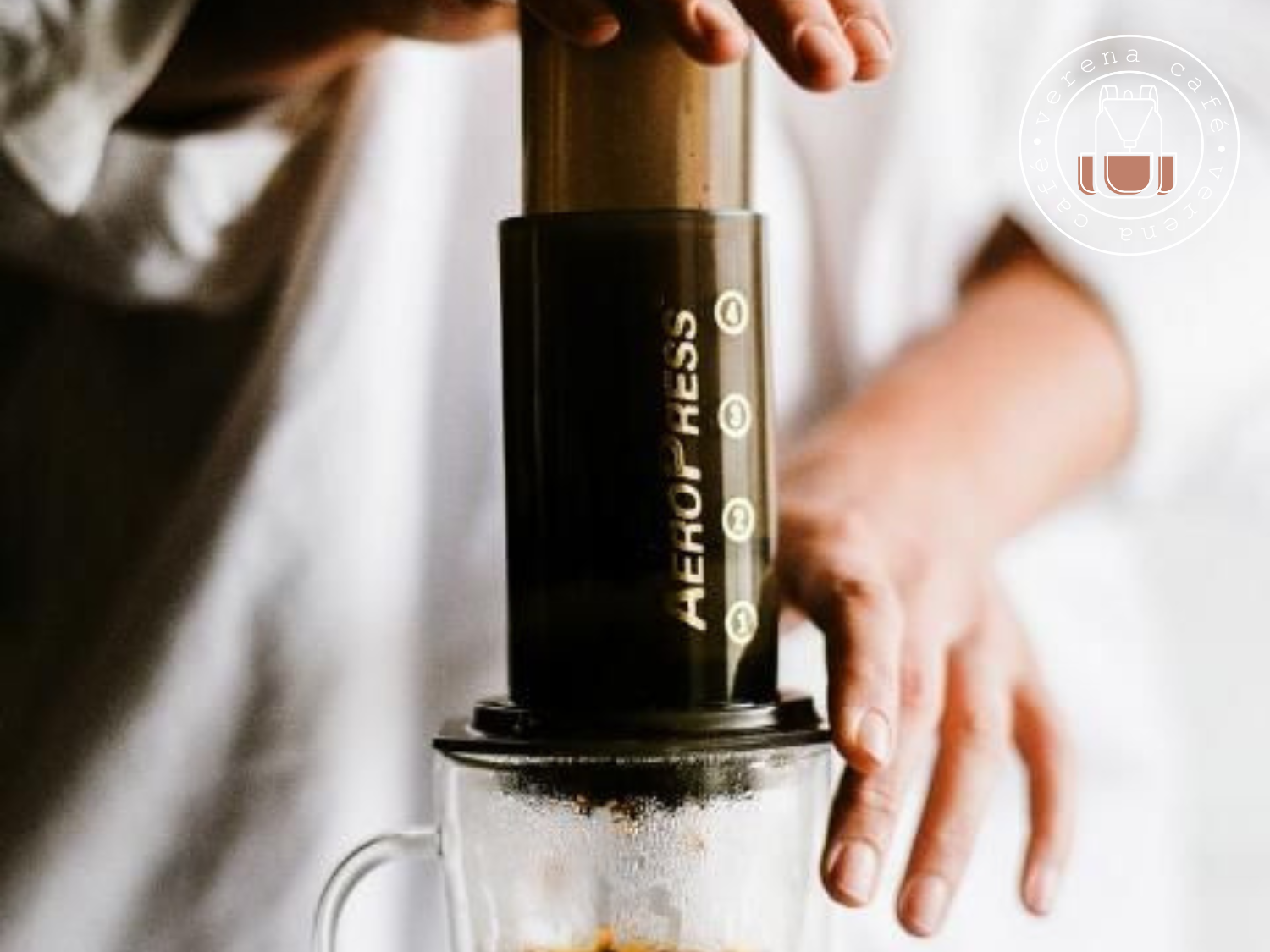 Imagem de uma AeroPress preparando café espresso em uma mesa com xícara de café especial.